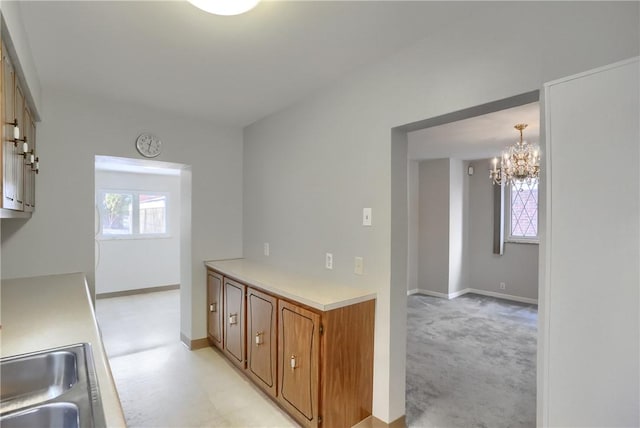 kitchen with pendant lighting, sink, and light colored carpet