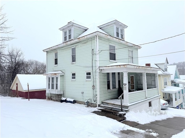 snow covered back of property with a porch