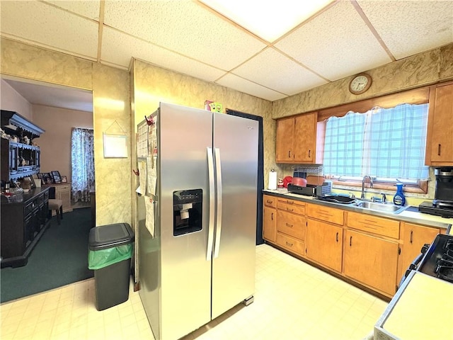 kitchen featuring stainless steel fridge with ice dispenser, sink, range, and a drop ceiling