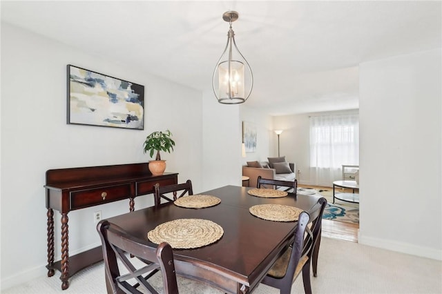 carpeted dining room with an inviting chandelier