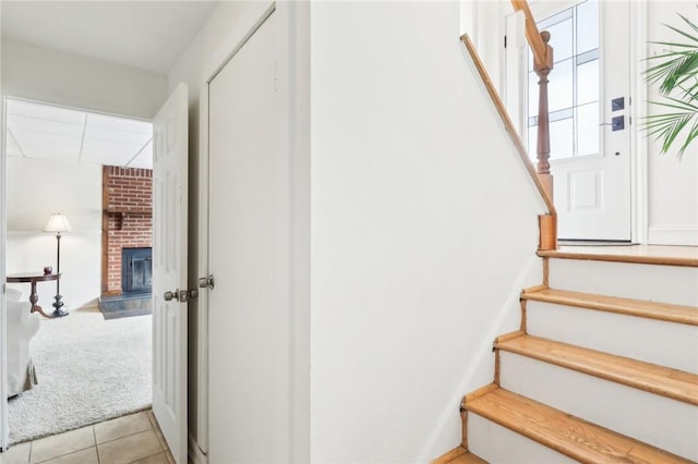 stairs with a brick fireplace and carpet flooring