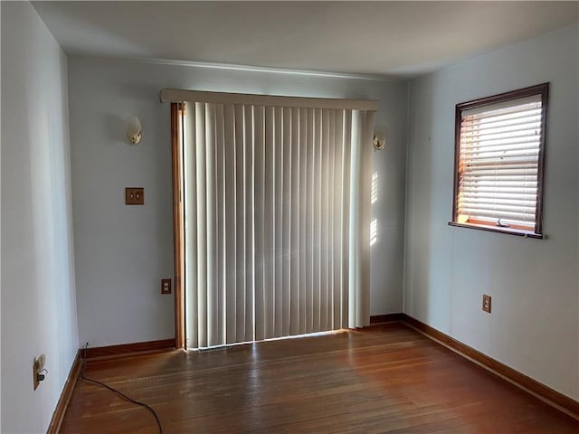empty room with wood-type flooring and baseboards