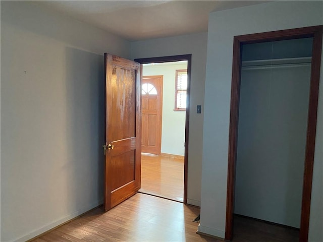 unfurnished bedroom with light wood-type flooring, baseboards, and a closet