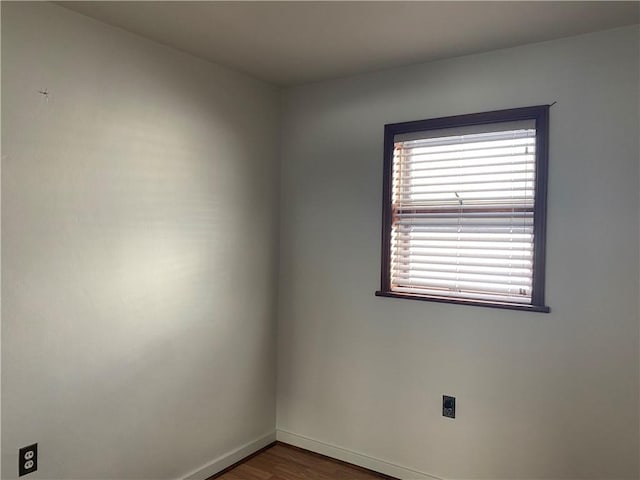 spare room with baseboards and dark wood finished floors