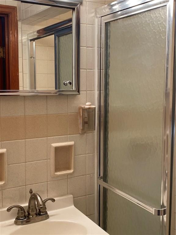 full bath featuring a sink, tile walls, and a shower stall