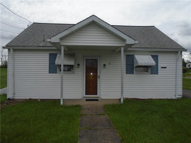 bungalow-style home with roof with shingles and a front yard