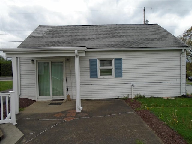 rear view of house featuring roof with shingles and a patio area