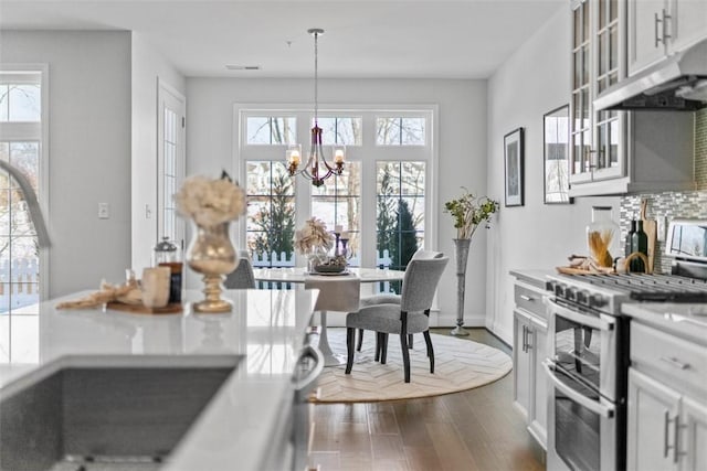 kitchen featuring double oven range, a chandelier, hanging light fixtures, and white cabinets