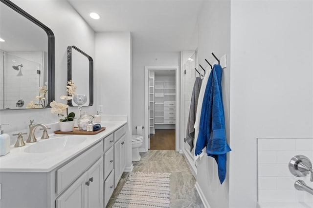 bathroom with a shower with door, vanity, and toilet