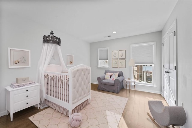 bedroom featuring wood-type flooring and a crib