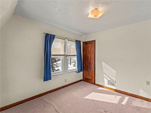 carpeted empty room featuring a textured ceiling