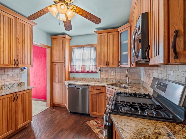 kitchen featuring light stone countertops, dark wood-type flooring, stainless steel appliances, sink, and backsplash