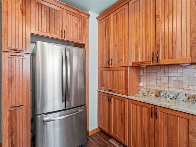 kitchen featuring light stone counters, stainless steel fridge, and tasteful backsplash