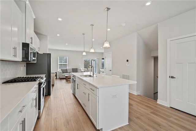 kitchen with pendant lighting, sink, white cabinetry, a kitchen island with sink, and stainless steel appliances