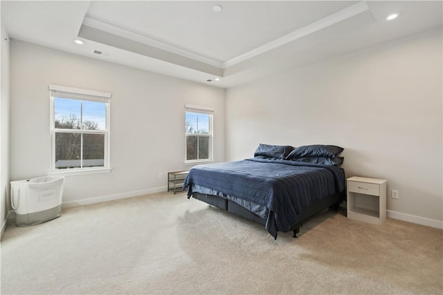 bedroom featuring light carpet, multiple windows, and a tray ceiling