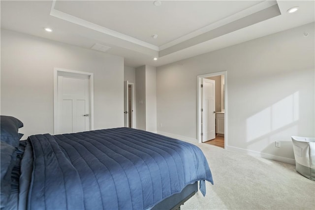 bedroom with a raised ceiling, crown molding, carpet floors, and ensuite bath