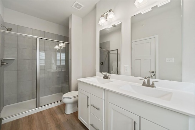 bathroom featuring a shower with shower door, hardwood / wood-style flooring, toilet, and vanity