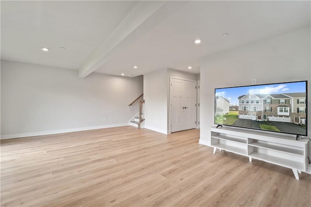 unfurnished living room with beamed ceiling and light hardwood / wood-style flooring