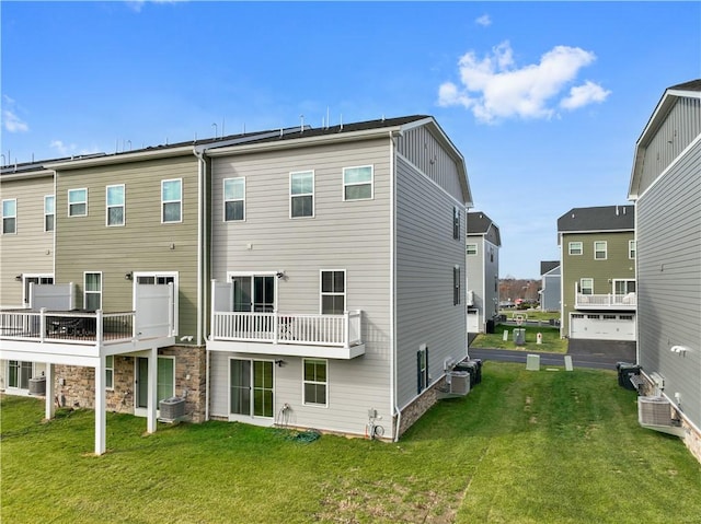 rear view of house featuring central AC unit and a yard