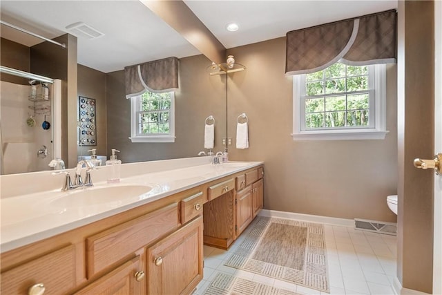 bathroom featuring toilet, a healthy amount of sunlight, a shower with door, and vanity