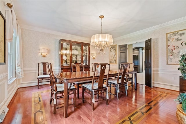 dining space with hardwood / wood-style flooring, a chandelier, and ornamental molding