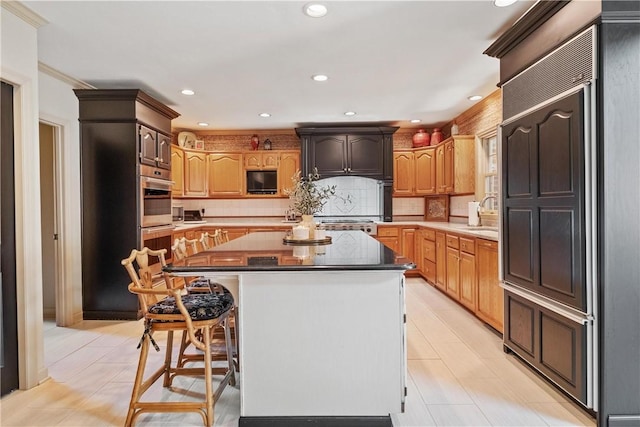 kitchen with double oven, sink, a breakfast bar, a kitchen island, and decorative backsplash