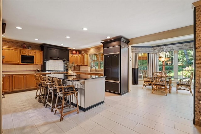 kitchen featuring decorative backsplash, sink, a kitchen island, ornamental molding, and a breakfast bar area