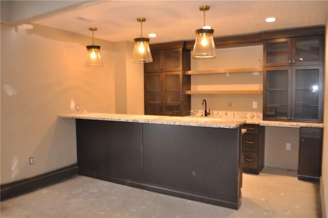 bar with decorative light fixtures, sink, light stone counters, and dark brown cabinets