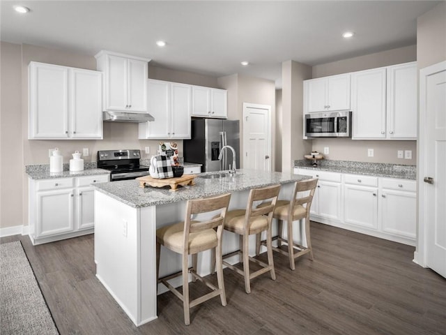 kitchen with stainless steel appliances, a kitchen island with sink, white cabinets, and a kitchen breakfast bar