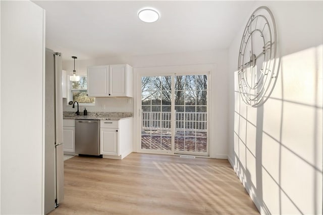 kitchen featuring light hardwood / wood-style flooring, hanging light fixtures, white cabinets, light stone counters, and stainless steel appliances