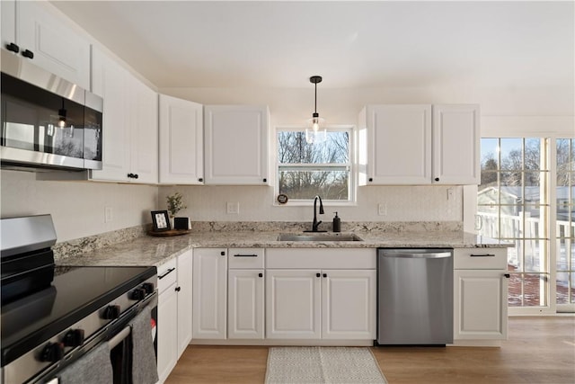 kitchen with sink, white cabinetry, appliances with stainless steel finishes, and pendant lighting