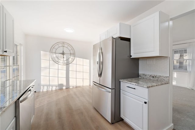 kitchen with light stone counters, tasteful backsplash, white cabinetry, and appliances with stainless steel finishes