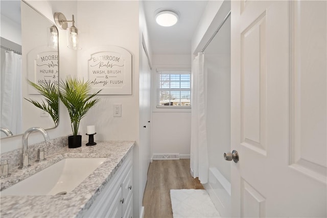 bathroom featuring hardwood / wood-style flooring, shower / tub combo with curtain, and vanity