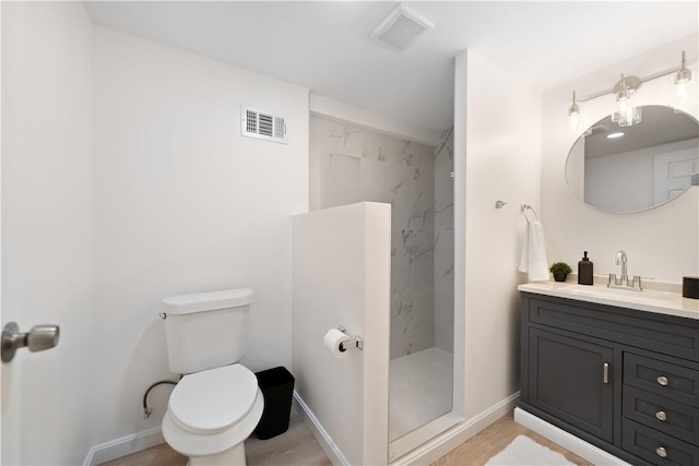 bathroom featuring vanity, toilet, and a tile shower