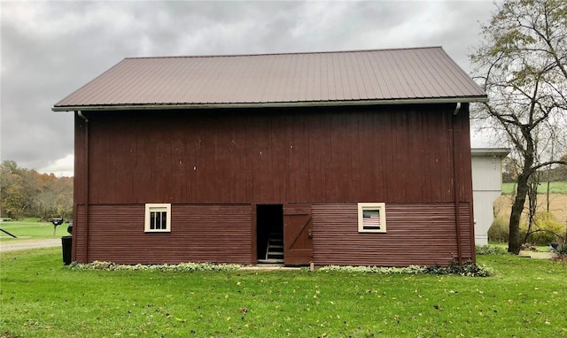 rear view of property featuring a lawn and an outbuilding