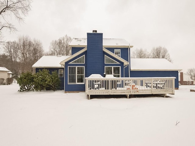 snow covered back of property with a wooden deck