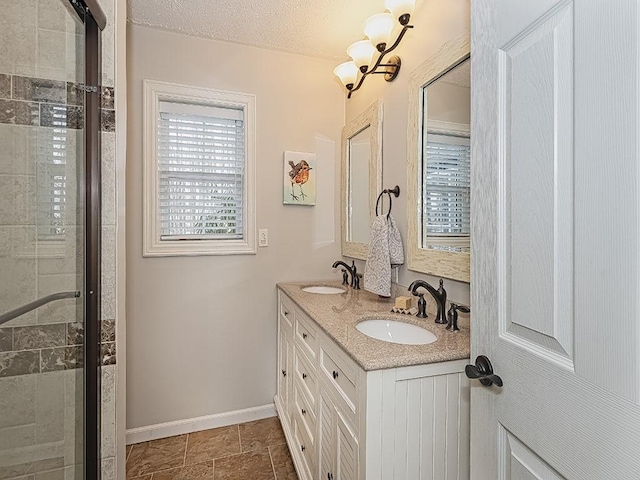 bathroom with vanity, a textured ceiling, and a shower with shower door