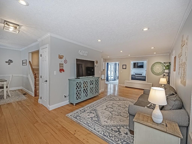 living room with ornamental molding, a textured ceiling, and light wood-type flooring