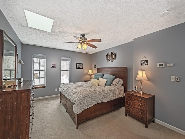 carpeted bedroom with a textured ceiling, ceiling fan, and a skylight