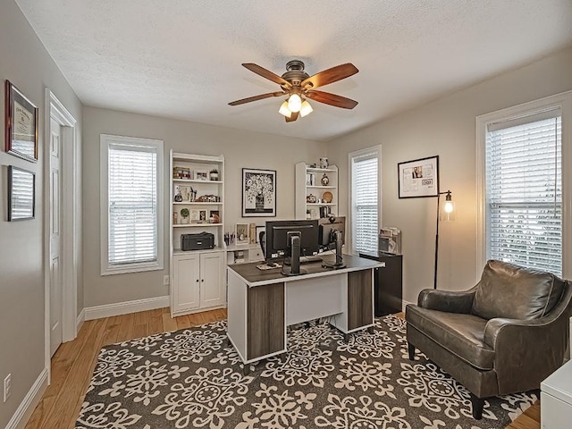 office with plenty of natural light, light wood-type flooring, built in features, and a textured ceiling