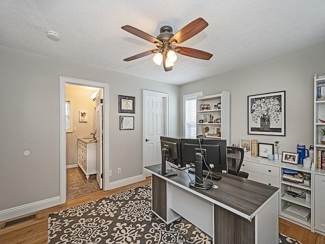 office featuring ceiling fan, dark wood-type flooring, and a textured ceiling