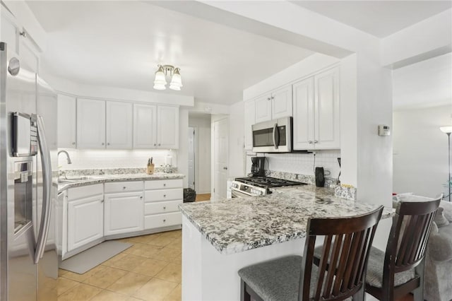 kitchen with sink, white cabinets, appliances with stainless steel finishes, and kitchen peninsula