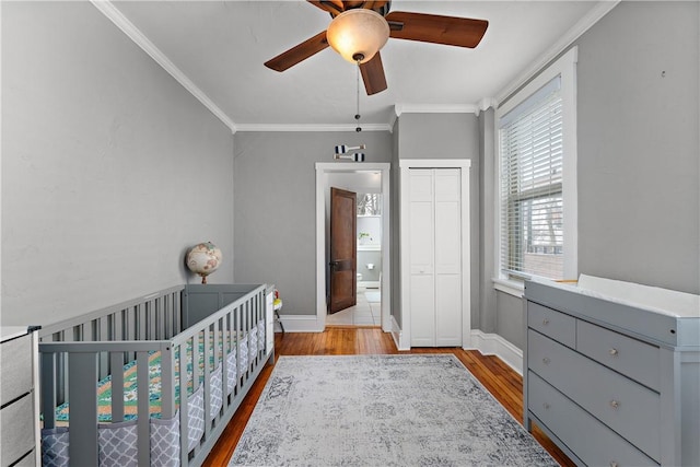 bedroom featuring a closet, ceiling fan, a nursery area, and light hardwood / wood-style flooring