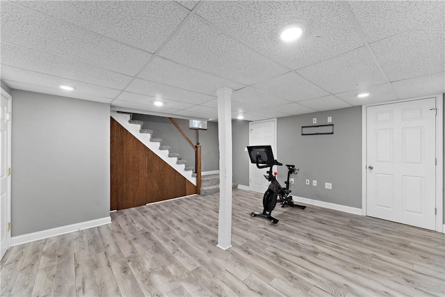 exercise area with a paneled ceiling and light hardwood / wood-style flooring