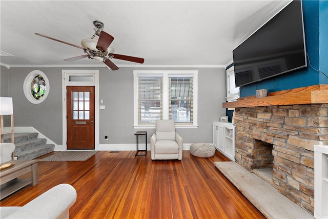 unfurnished living room featuring crown molding, hardwood / wood-style floors, ceiling fan, and a stone fireplace