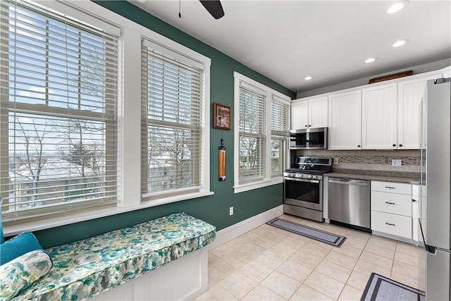 kitchen with white cabinetry, light tile patterned floors, backsplash, stainless steel appliances, and plenty of natural light