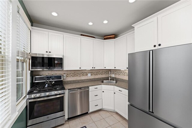 kitchen with sink, white cabinetry, light tile patterned floors, and stainless steel appliances