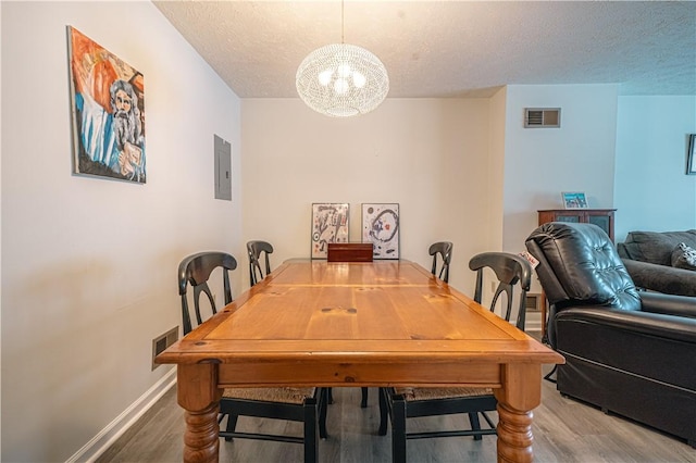 dining room with a textured ceiling, dark hardwood / wood-style floors, and electric panel