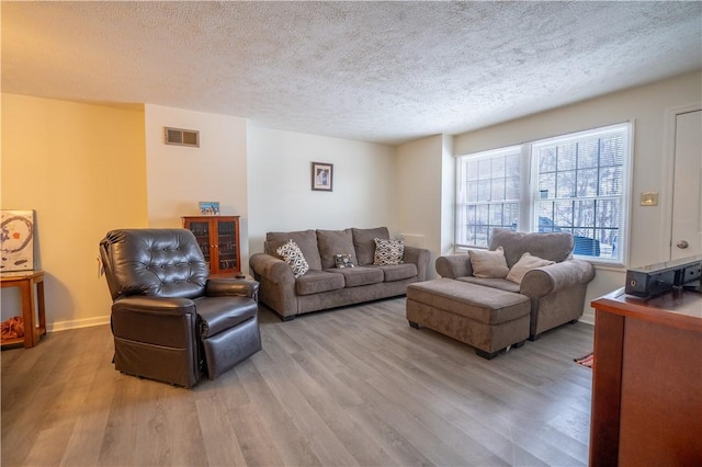 living room with a textured ceiling and light hardwood / wood-style flooring