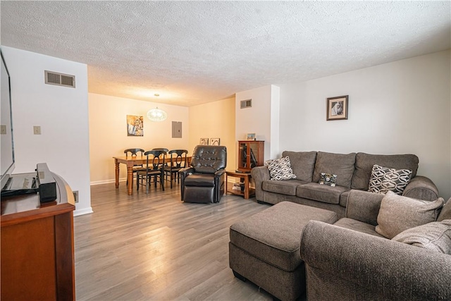 living room featuring electric panel, a textured ceiling, and wood-type flooring